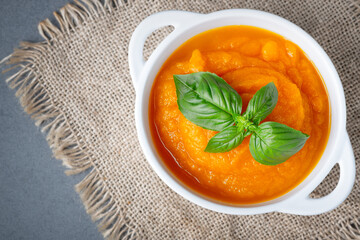 Bowl of delicious autumn pumpkin soup on a gray table