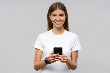 Student girl in white mockup t-shirt using smart watch synchronized with smartphone in her hands