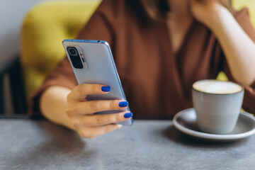 Young woman in cafe with smartphone in hands, manicured nails. 