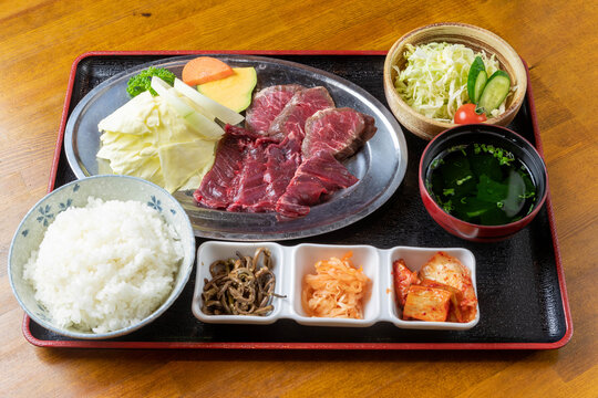新鮮な牛カルビとハラミ肉に彩り豊かな野菜を添え、肉厚で柔らかな質感を閉じ込めた「牛焼肉定食」。素材の輝きが際立つ一膳で、ランチや焼肉店の販促に最適な高品質素材です。 | Japanese beef karbi and harami set meal with fresh vegetables and rice.