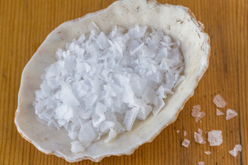 Salt crystals in sea shell on wood table, natural organic salt top view photo