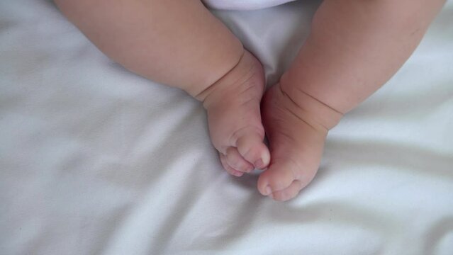 Close up of foots baby in a room with a lot of sunlight. The newborn sleeping on the mother's bed. Health care, love and relationship concept.