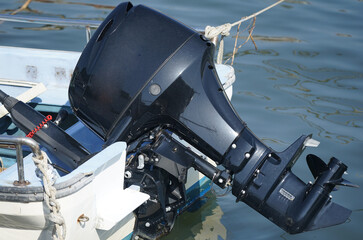 Black outboard motor attached to a boat in the harbor