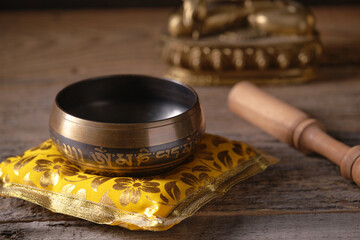 Tibetan singing bowl with engraved mantra „Om Mani Padme Hum“ on a wooden table. The text on...