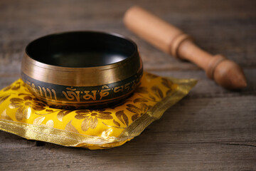 Tibetan singing bowl with engraved sanskrit mantra „Om Mani Padme Hum“ on a wooden table. The...