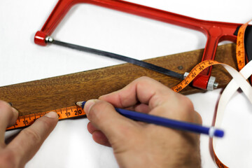 Engineer calculating the length of a wooden piece with a ruler, marking spots to where to cut, ready to saw wider angle