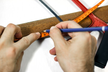 Engineer calculating the length of a wooden piece with a ruler, marking spots to where to cut, ready to saw