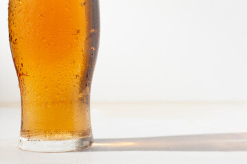 Cold light beer, best offer in pub. Water drops on glass of beer, on white background, free, empty space for text, studio shot, side view close up.