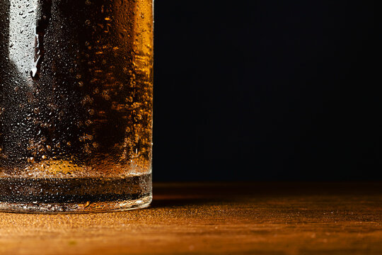 Cold light beer in a mug, on a wooden table and a dark background with blank space for a logo or text. Stock Photo mug of cold light beer close-up.