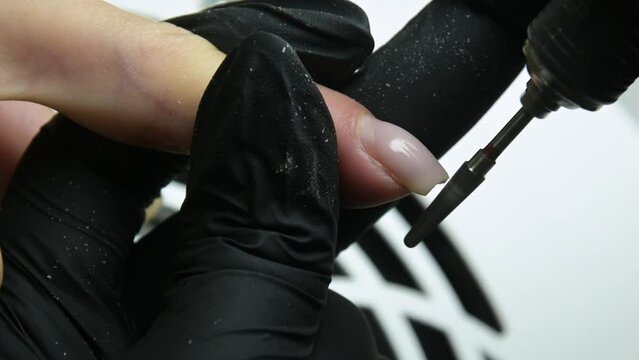 the master in the beauty salon removes the client's extended nail with a special tool. sawdust milling cutter in 4k
