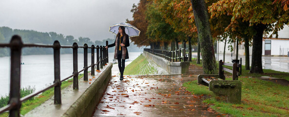 Young woman with umbrella walking in the autumn rain