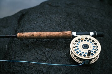 Closeup of an old Shakespeare fly rod design with a gold reel on a rock - Powered by Adobe