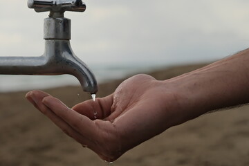 Hand holding water tap. Significant shortage of clean water resources