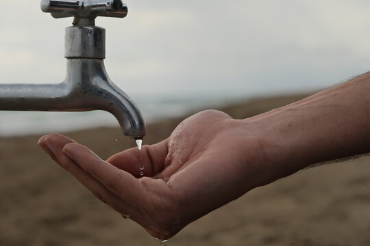 Hand Holding Water Tap. Significant Shortage Of Clean Water Resources