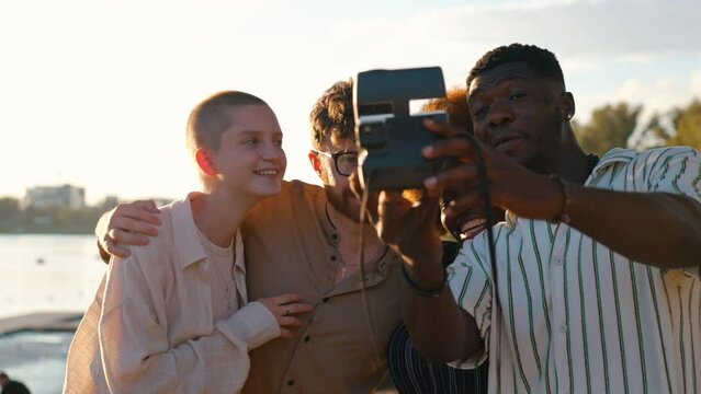 Interracial friendship. Group of happy close friends, reunited on their camping van trip, traveling through the country. Laughing and taking selfies together near the river. High quality 4k footage