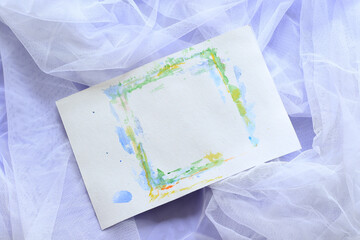 empty paper sheet with aquarelle green frame on white tulle with purple backgrpund