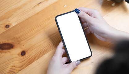 hand woman using a telephone, empty screen smart phone and computer on wooden table top view.