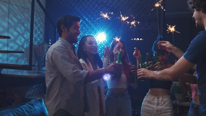 Diverse  young people clinking beer and waving sparkler on night party