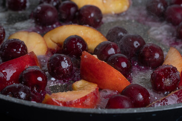 Close-up of delicious, caramelized cherries and nectarines in pan. Appetizing pan-fried fruits for dessert. Excellent image for homemade dessert banners and advertisements.