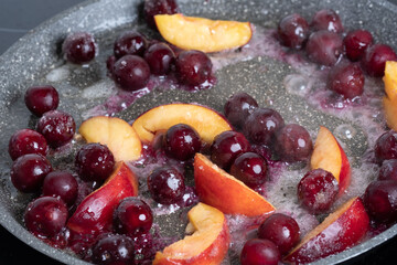 Close-up of delicious, caramelized cherries and nectarines in pan. Appetizing pan-fried fruits for dessert. Excellent image for homemade dessert banners and advertisements.

