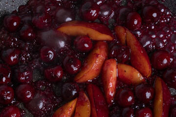Close-up of delicious, caramelized cherries and nectarines in pan. Appetizing pan-fried fruits for dessert. Excellent image for homemade dessert banners and advertisements.
