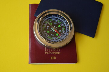 Red and blue passport with compass on yellow background, finding the right destination in the world for travel and business