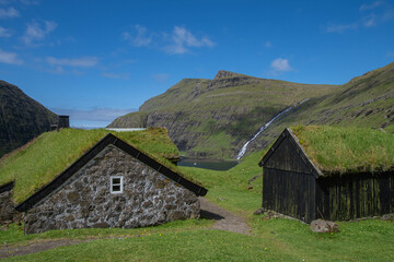 Fototapeta na wymiar Wasserfall und Häuser mit Grasdach in Saksun, Insel Streymoy, Färöer-Inseln