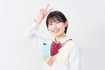 白背景でスマホを持ってピースする女子高生