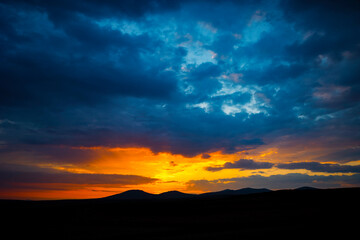 Sunset or sunrise over the hills with dramatic clouds. Peace or heaven concept