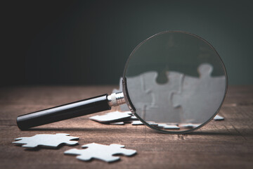 a magnifying glass and puzzle pieces on the table