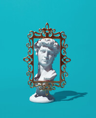 Male bust, popular travel souvenir, creative arrangement on turquoise blue background. 