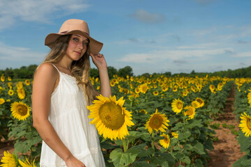 A Lovely Blonde Model Poses Outdoor While Enjoying The Summer Weather In A Field Of Wild Sunflowers