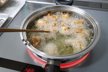 鶏の唐揚げ、からあげ、から揚げ、唐揚。米油で揚げている調理シーン。