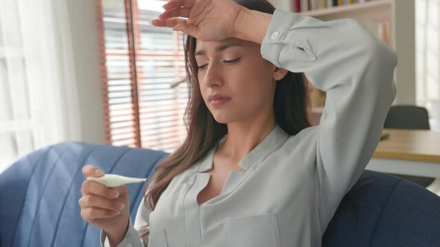 Woman sick and fever look at thermometer worried about coronavirus