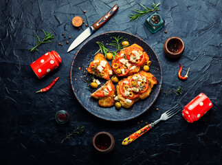 Meat schnitzel with cheese, olives and tomato