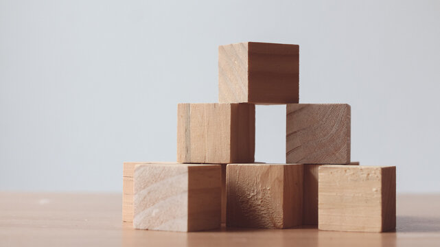 Wood cube on top of wood block tower Business risks.