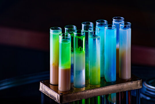 Colorful Shot Drinks In Glass Tubes. Dark Background, Atmospheric Bar Image. Laboratory Glassware With Alcohol Cocktails On Chemical Party.