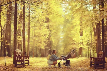 Fotobehang moeder met een kinderwagen in het herfstpark voor een wandeling, landschap herfstzicht oktober steegje geel park © kichigin19