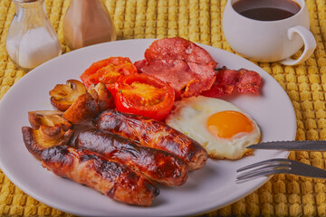 Cooked full English breakfast with a cup of coffee, Shot on a yellow surface.