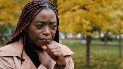 Close-up young african american woman standing outdoors coughing holding neck suffering from sore...