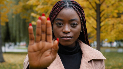 Close-up young serious focused angry african american woman holding palm in front showing stop...