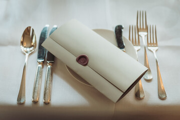 Festive table setting. Guest note with wax seal on a plate