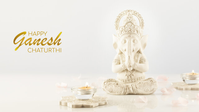 Holiday of Ganesh Chaturthi. Greeting card with Sculpture of ganesha, rose petals and candles on a light background with congratulation text. Lord Ganesha, Ganesh festival. Hindu religion holiday