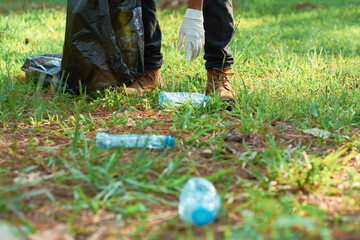 Hispanic teenage male volunteer collects plastic garbage from the forest. Environmental awareness concept.