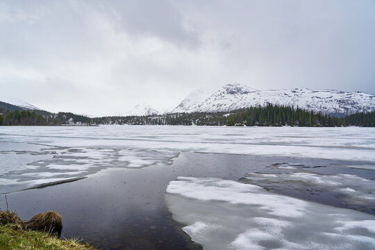 frozen lake in the Norwegian highlands with snow-capped mountain in the background