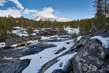 River in snowy landscape with mountains in the background in Norway