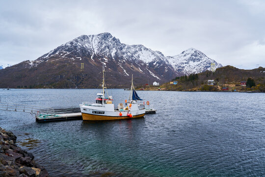 fishing boat moored in a Lofoten fjord with a snow-capped mountain behind it