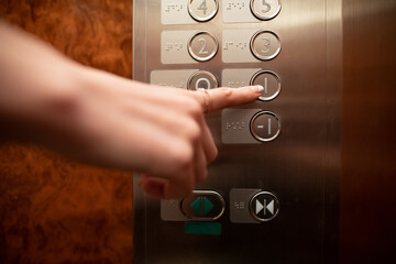エレベーターのボタンを押す女性の手