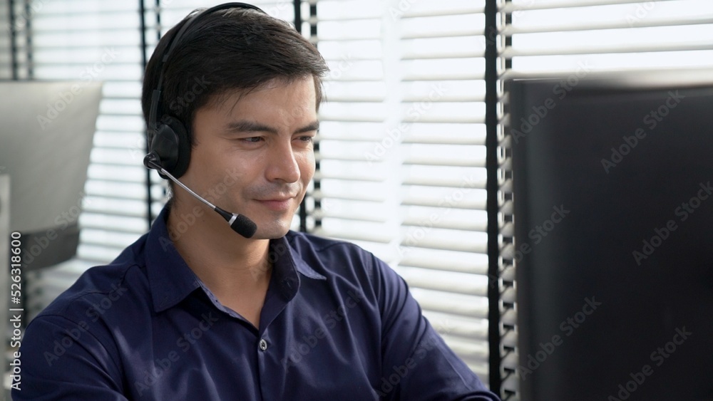 Aufkleber young competent asian male call center agent working at his computer while simultaneously speaking w