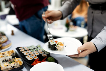 close-up of female hands pouring different sushi on a plate
